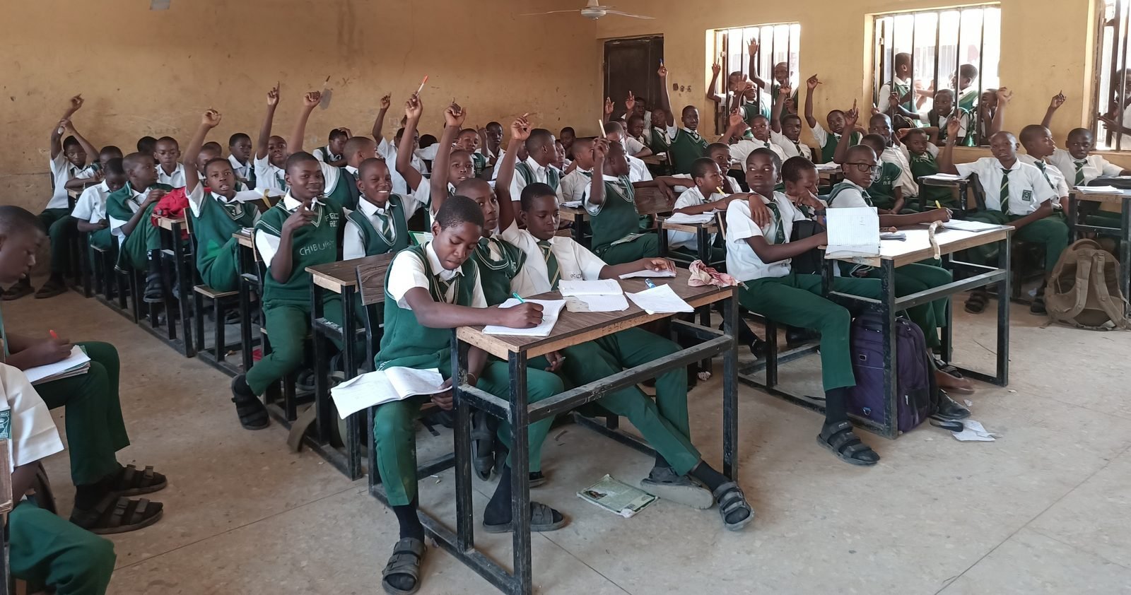 A classroom of engaged students raising their hands in the DR Congo