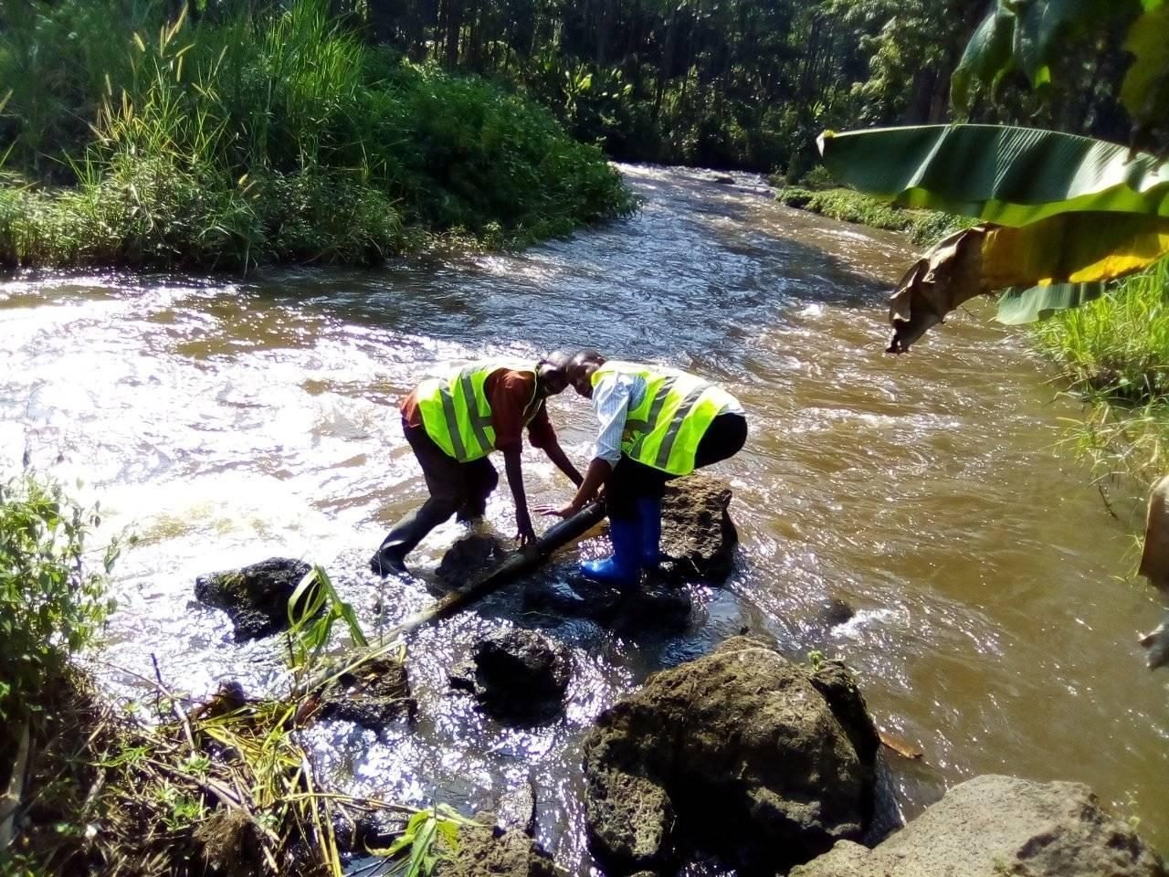Two PALPER staff in safety vests working in a river in North Kivu, DR Congo