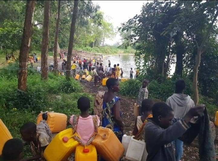 People waiting with jerrycans at the water edge in North Kivu, DR Congo