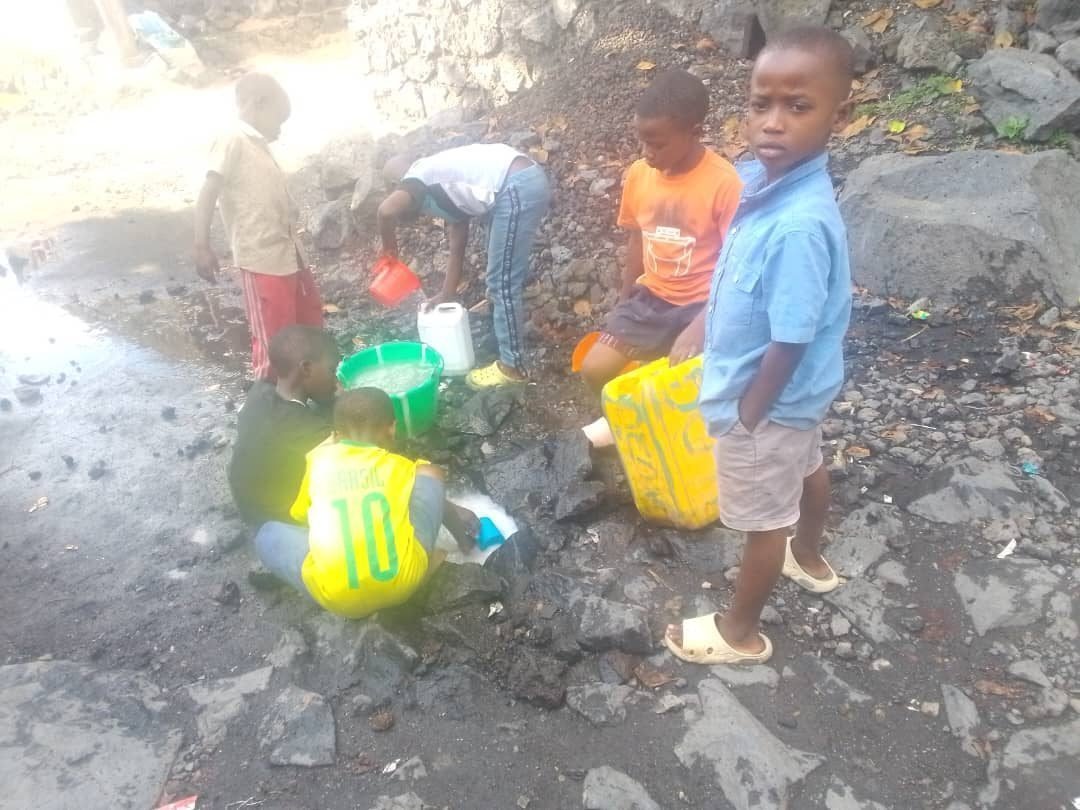 Children collecting water from pools on volcanic rock in Goma, DR Congo