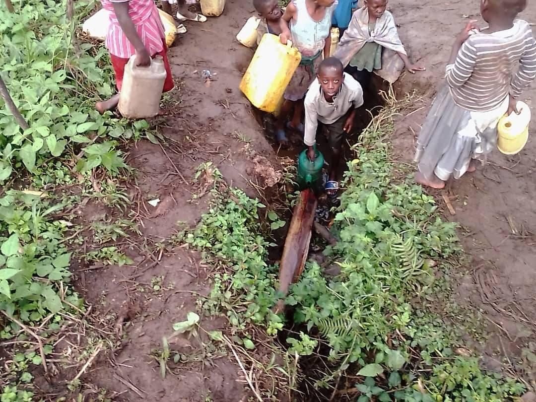 Children filling jerrycans from a muddy channel of water in North Kivu, DR Congo